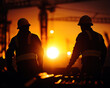 © Moonroad - Silhouetted construction workers observe a stunning sunset, symbolizing dedication and hard work in the industrial landscape.