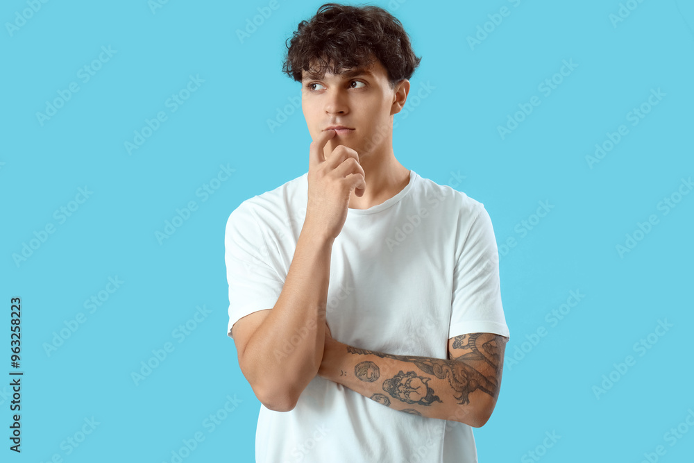 Portrait of pondering young man on blue background