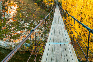 Wall Mural - A bridge over a river with a view of the trees and rocks below