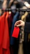 © Aamir - Woman holding out a red tag in front of an expensive rack, price discount, luxury shopping