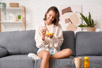 Canvas Print - Pretty young woman with pill organizer sitting on sofa at home