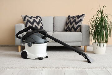 Poster - Modern vacuum cleaner on carpet near grey sofa at home