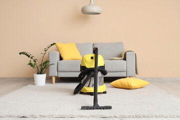 Canvas Print - Modern vacuum cleaner on carpet near grey sofa at home