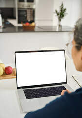 Over shoulder vertical photo of middle aged woman customer looking at white mock up blank screen using laptop computer at home table doing online shopping, searching on web. Website mockup display.