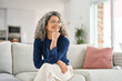 © insta_photos - Happy relaxed 50 years old woman sitting on sofa at home looking away. Smiling middle aged lady posing in living room at home. Mature older female with curly gray hair relaxing on couch enjoying chill