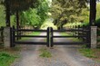© anatolir - Gravel driveway is passing through a wooden gate leading to a countryside property surrounded by trees
