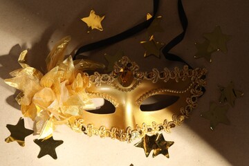 Canvas Print - Beautiful golden carnival mask and confetti on beige background, closeup