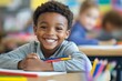 © Tida - A young African American boy sits at his desk in a classroom, smiling brightly as he holds colored pencils. The image represents the joy of learning, creativity, and the positive atmosphere of a schoo