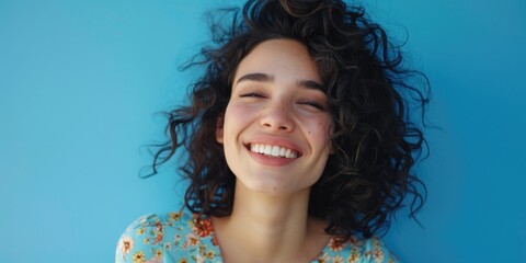 Sticker - A woman with curly hair is smiling and looking at the camera. She is wearing a blue floral dress