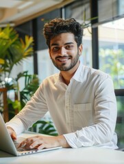 Wall Mural - A man is sitting at a desk with a laptop in front of him. He is smiling and he is happy