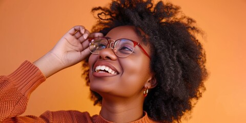 Poster - A woman with curly hair is smiling and wearing glasses. She is wearing a red sweater and has a pair of red earrings