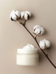 Wall Mural - A jar of white cream is on a table next to a branch of cotton flowers. The flowers are arranged in a way that they are leaning on the jar, creating a sense of balance and harmony