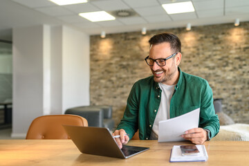 Wall Mural - portrait of handsome manager analyzing financial reports over computer at his workplace in modern of
