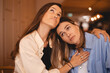 © zvkate - Portrait of displeased young woman and best female friends sisters trying to comfort and cheer up sitting together in cafe. Women hugging to support her friends. Bad news.