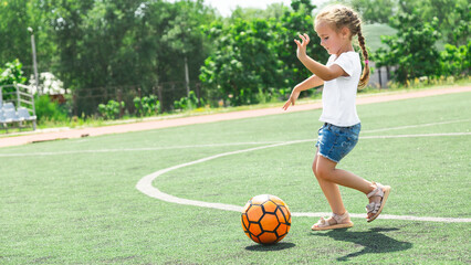 Little girl playing with a soccer ball on outdoor sports fields