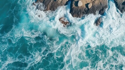 An aerial view of the ocean with whitecaps crashing against the rocks.