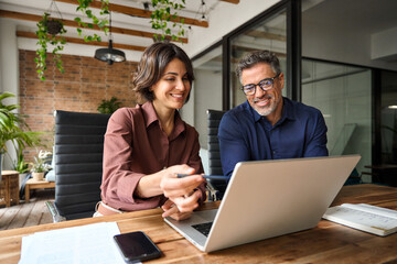 business team of two executives working together using laptop in office. happy young business woman 