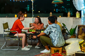 Group of Happy Asian people friendship enjoy and fun celebration meeting dinner party eating Korean food barbecue grill and drinking alcohol at outdoor rooftop on summer holiday vacation night.