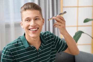 Poster - Young man with smartphone listening to voice message at home