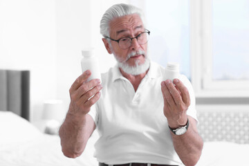 Poster - Senior man with bottles of pills on bed indoors, selective focus