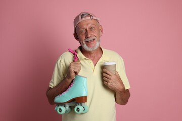 Sticker - Portrait of happy senior man with paper cup and roller skates on pink background