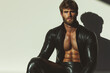 © Augustino - Famous Gay, Queer Art concept. Portrait of a handsome biker bodybuilder with beard wearing black leather clothing, posing on white background. Text space. Studio shot