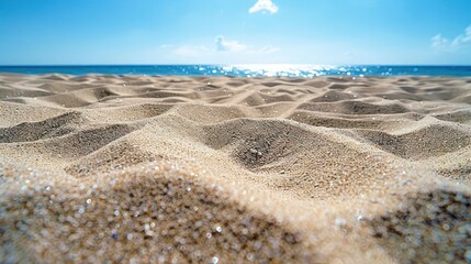 Closeup of soft, white sand beach with rippled texture and the ocean and sky in the background.