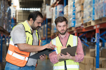 Wall Mural - Warehouse concept. Two male warehouse worker working and checking boxes of products on shelf in warehouse. Group of two male worker at warehouse