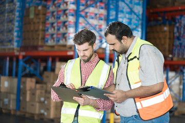 Wall Mural - Warehouse concept. Two male warehouse worker working and checking boxes of products on shelf in warehouse. Group of two male worker at warehouse