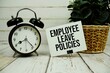 © may1985 - Employee Leave Policies text on paper card with alarm clock on wooden background