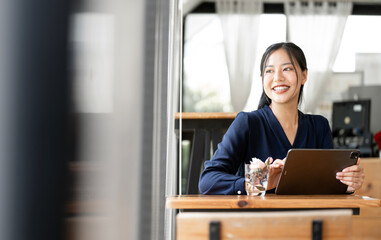 Wall Mural - beautiful asian businesswoman in the cafe, using digital tablet and smiling, looking up.