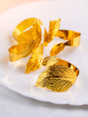 Close up of decorative gold metal napkin rings with leaves on light table