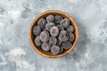 Sun-dried organic prunes in wooden bowl top view