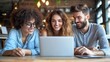 © Anna - A group of three friends, two women and a man, share smiles and laughter as they engage with a laptop in a bright cafГ©, creating a lively atmosphere around them