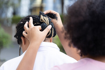 One young African woman help making hair to her friend or sister, braided Afro hair styling