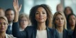 © Ahmed - Businesswoman raising her hand. She is answering a question during a business conference or job training seminar. Group of diverse people are wearing business clothing