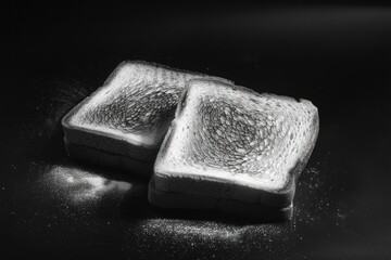 Two slices of toast with a sprinkle of salt on top. The image has a simple and minimalistic feel to it, with the focus being on the bread and salt