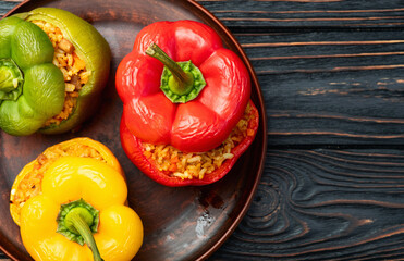 Wall Mural - Baked stuffed pepper ( paprika ) with rice , carrot and meat . Top view on rustic background