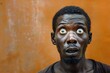 © Minerva Studio - Close-up portrait of a thin senegalese man against an orange backdrop, featuring an intense expression with extremely wide open eyes, conveying shock and surprise in high-quality detail