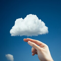 Wall Mural - Hand reaching towards a white cloud in the blue sky.