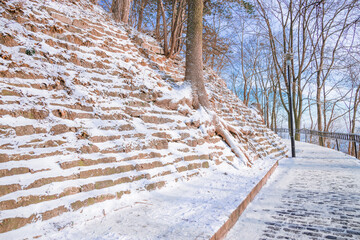 winter idyllic peaceful picturesque landscape town park square with hill terraces trees and lantern along road around top, frosty snowy December season weather bright day time