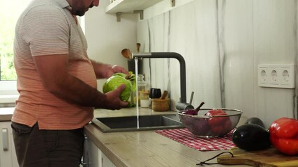 Wall Mural - Man is washing cabbage at the kitchen