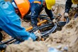 © Victor Bertrand - Blue and yellow helmeted workers manipulate thick, black cables in a sandy trench, highlighting cooperation and labor intensity.