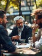 © vefimov - Three men sitting at a table, one of them is wearing glasses and has a beard. They are talking and drinking water