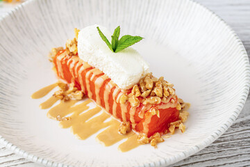 Pumpkin dessert with tahini and walnuts on a porcelain plate