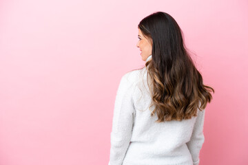 Wall Mural - Young Italian woman isolated on pink background in back position and looking side