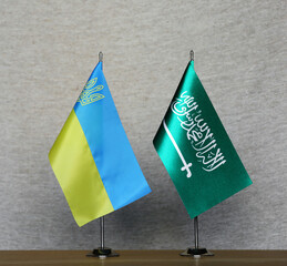 Table flags of Ukraine and Saudi Arabia on a gray blurred background