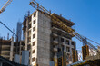 © Grispb - Scenery with buildings under construction. Crane boom over construction site. Erection of multi-storey buildings. Process of building houses with residential apartments. Erection monolithic buildings