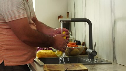 Wall Mural - Man is washing corn at the kitchen