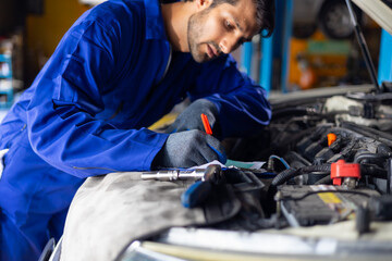 Close up hand hispanic latin male mechanic repairs car in garage. Closeup hand. Auto car mechanic checking the oil level of the car engine. Car repair and maintenance